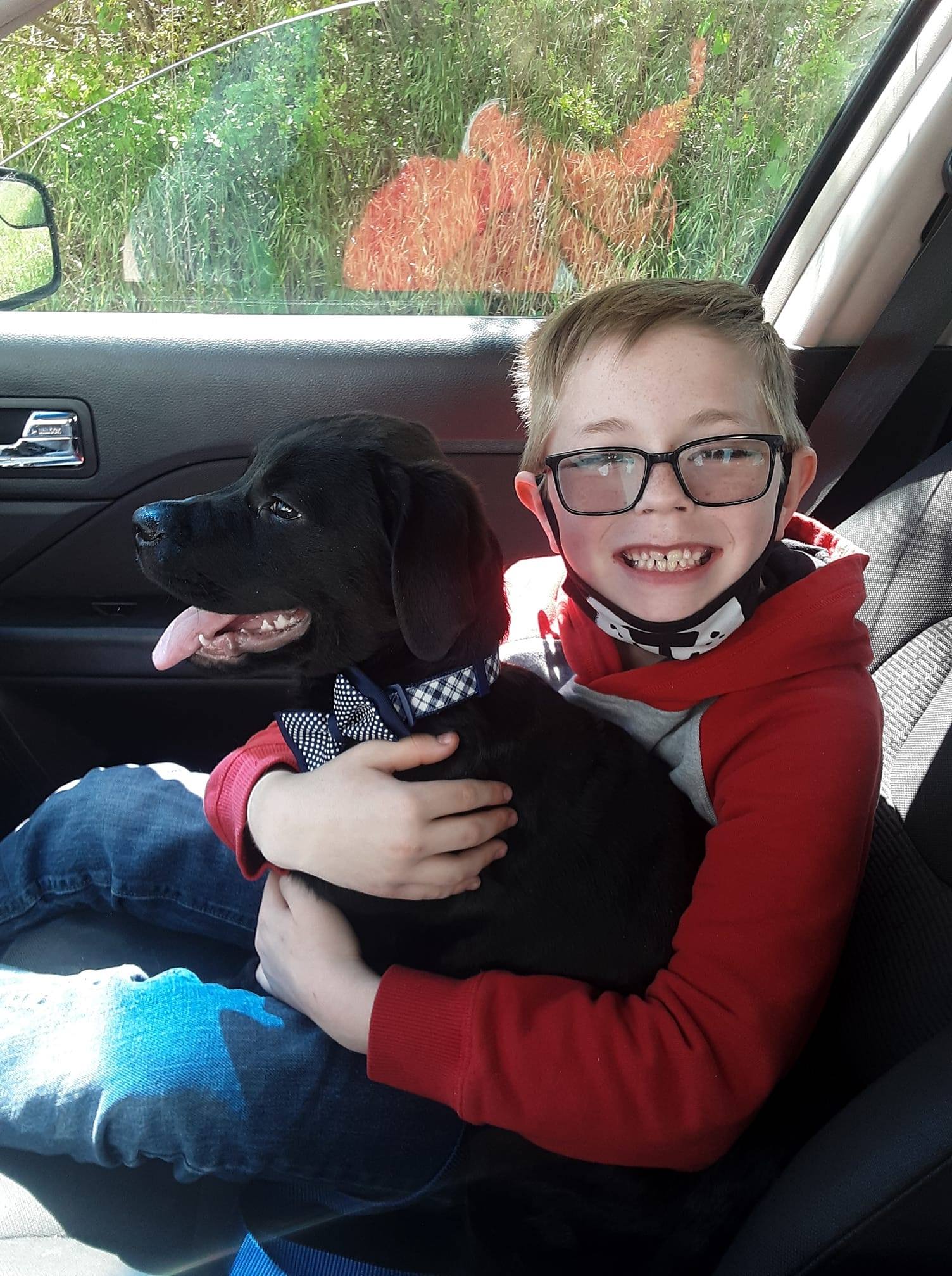 boy holding pup in his arms in a car