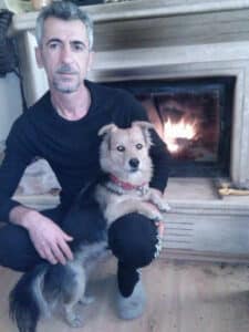 man holding a dog in front of a fireplace